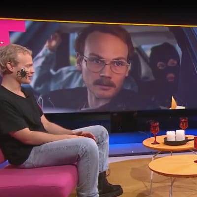 Näyttelijä Elias Salonen Puoli seitsemän -ohjelmassa pinkillä sohvalla istumassa. 
