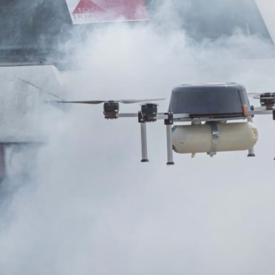 Pelastuslaitoksen drone savupilven keskellä auton edessä.