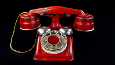 En röd telefon med roterande nummerbricka.