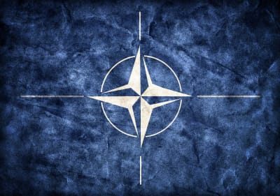 Natos flagga, en vit symbol mot blå bakgrund.