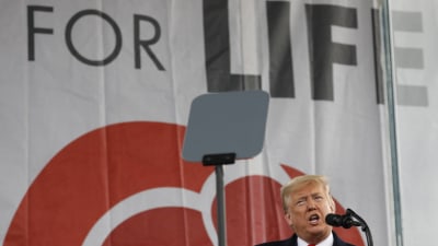 Donald Trump står och talar i en mikrofon på en scen.