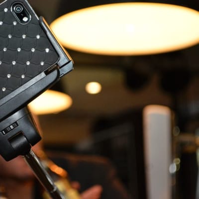 Juhlijat ottavat ravintolassa kuvaa itsestään älypuhelimen ja selfie-kepin avulla.