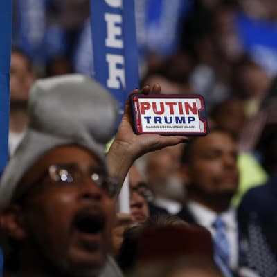 Kuva ihmismassasta Philadelphian puoluekokouksessa. Väkijoukon keskellä joku pitää esillä kännykkää, jonka näytöllä lukee: "Putin. Trump. Making Russia Great Again."