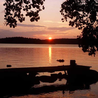 Auringonlasku järven rannalla.