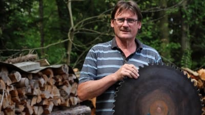 Den tyske korttidsarbetaren Hans Pfister har reparerat sin såg och håller upp ett vässt cirkelblad