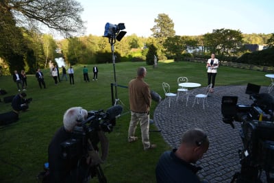 Danmarsk statsminister Mette Frederiksen pratar med journalister utomhus, med flera meters avstånd mellan alla människor. 