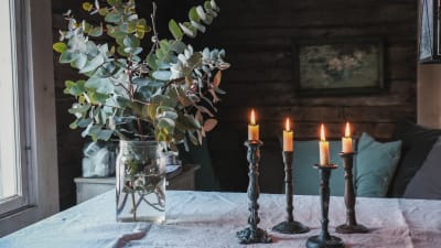 Maljakossa eukalyptuksia, pöydällä kynttilöitä, saunan vilvoittelutila