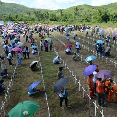 Taifuuni Haiyanista selviytyneet ja taifuunissa menehtyneiden omaiset laskivat kukkia haudoille Taclobanissa Filippiineillä 8. marraskuuta 2014.  