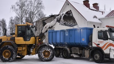 Snöröjning, snö stjälps över på en lastbil.