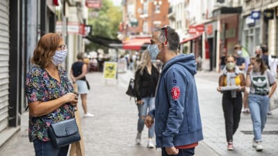 Nainen ja mies keskustelevat kadulla maskit kasvoillaan.