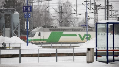 Tåg åker förbi snöig tågstation