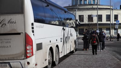 Ihmisiä nousee bussiin Turun linja-autoasemalla