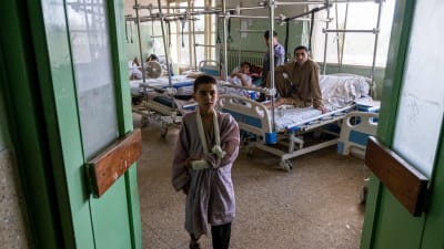 En avdelning vid ett sjukhus i Kabul där skadade i en terrorattack vårdas. En pojke med armen i bandage står i förgrunden och flera män ligger på sjukhussängar i bakgrunden.