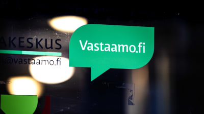 Logotyp i form av en grön pratbubbla och med texten vastaamo.fi på en glasdörr.