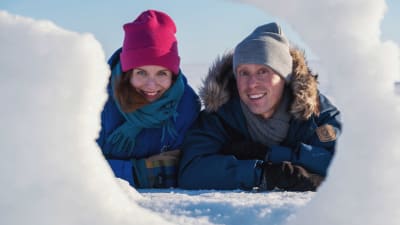 Egenlandin ohjelmajuontajat Nicke Aldén ja Hannamari Hoikkala kurkkaavat lumen takaa Hailuodossa.