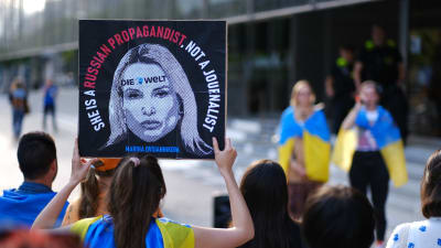 Ukrainska ungdomar demonstrerar i Berlin, de håller i en skylt där med texten "Marina Ovsjannikova. Hon är en rysk propagandist, inte en journalist"