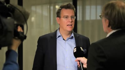 En man i skjorta och kavaj intervjuas för TV. 