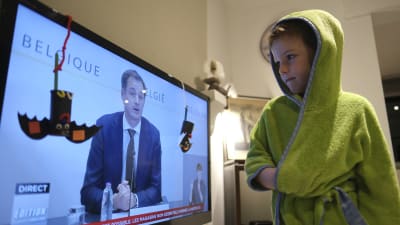 Den femåriga pojken Hugo tittar på regeringens presskonferens med sina föräldrar. 