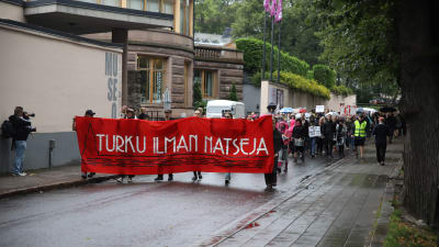 Demonstranter marscherar och bär en banderoll.