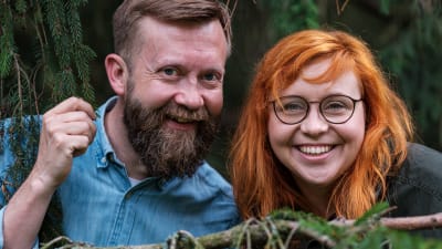 Närbild av Annika Ljungberg och Joakim Lax på en sten i skogen.