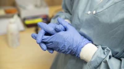 En skötare sätter handskar på händerna.