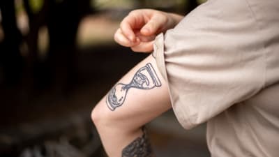 En arm som har en tatuering föreställande ett timglas på sig.
