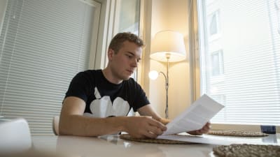 Antti Lehtinen läser ett brev vid ett bord.