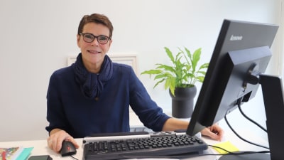 Elise Kurtén, rektor vid Sirkkala skola, sitter vid sin dator och ler mot kameran.