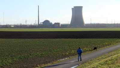 En man rastar sin hund vid kärnkraftverket Grafenrheinfeld.