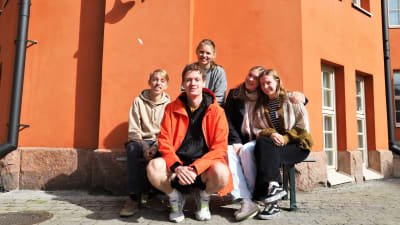 Ungdomarna Frida Laine, Oliver Helenius, Karl Wernstål, Melinda Eriksson, Jeelka Maria Jaspers, sitter på en bänk utanför Katedralskolan i Åbo