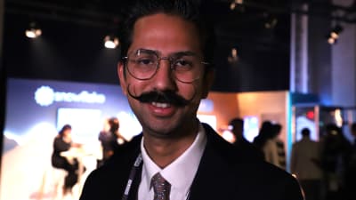 En leende man med glasögon och mustasch. 