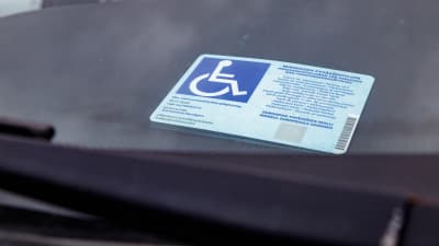 Vammaisen pysäköintilupa auton kojelaudalla.