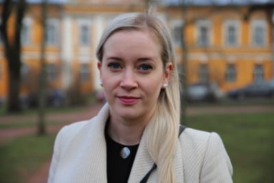 En ljushårig kvinna i halvbild ser in i kameran.
