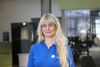 En kvinna med långt ljust hår, glasögon och en klarblå blus.