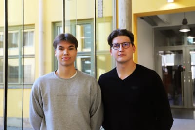 Två unga män som står i aulan i ASA-huset vid Åbo Akademi.