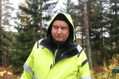 Jan Lindholm har på sig en reflexjacka och har skogen i bakgrunden.