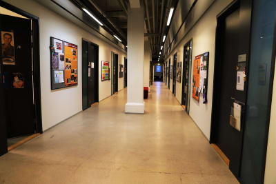 En korridor med betonggolv som kantas av väggar med planscher.