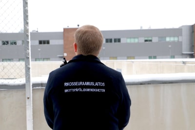 En väktares rygg utomhus vid Åbo fängelse.