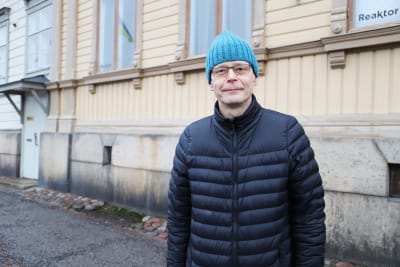 En medelålders man med glasögon ser in i kameran.