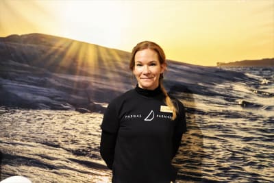 Kommunikatör Linda Baarman, i bakgrunden en bild av en havsklippa.