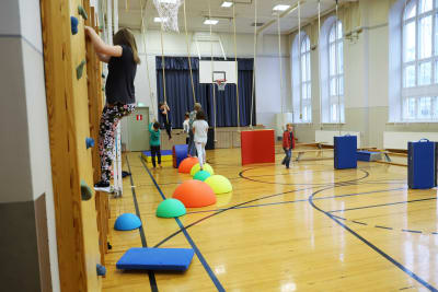 Barn leker i en gymnastiksal med färggranna hinder som placerats på en hinderbana.