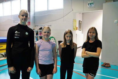 Fyra flickor står i en gymnastiksal.