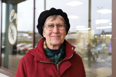 En äldre kvinna med svart basker och runda glasögon.