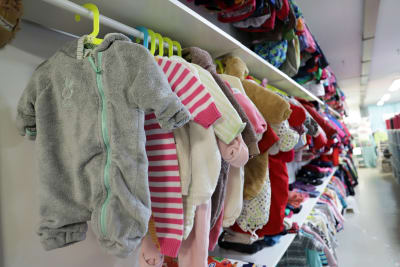 En lång rad med babykläder som hänger på klädhängare.