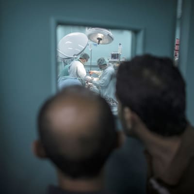 Miehet seurasivat Shifan-sairaalan ensiapuosastolla käynnissä olevaa operaatiota, jossa lääkärit koettivat perlastaa Israelin torille tekemässä iskussa vakavasti loukkaantuneen palestiinalaisen 30. heinäkuuta.