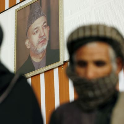 Afganistanin presidentti Hamid Karzain muotokuva näkyy entisten taliban-sotilaiden takana.