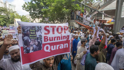 En demonstrant håller upp en affisch med texten Stop Burning Quran (Sluta bränna koranen) under en demontration mot koranbränning i Bangladesh.
