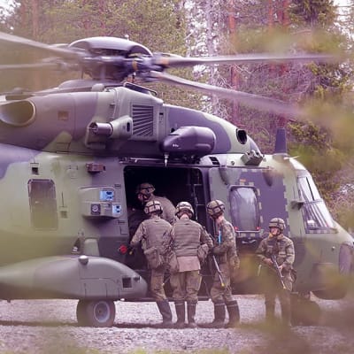 Varushenkilöt ovat nousemassa suuren kuljetushelikopterin kyytiin.
