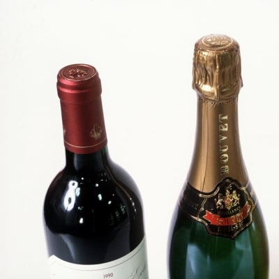 Kolme pulloa, joissa on puna- ja valkoviiniä sekä samppanjapullo.
