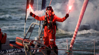 Yksinpurjehtija Ari Huusela tuulettaa soihdut käsissään maaliintuloa Vendée Globe -kilpailussa.